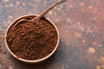 Bowl with cocoa powder on grunge background