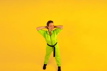 Full length body size photo of happy woman wear modern green overalls on bright yellow color background. Cheerful and energetic middle age female with colored make up having fun near copy space