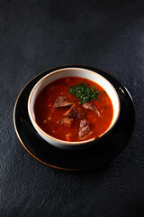 Traditional Russian soup. Cabbage soup - cabbage soup from sauerkraut. Bread croutons. He was lying flat. Black background. Vertical photo. Copy space.