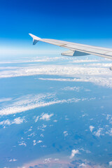 Fototapeta premium View from the airplane window at a beautiful cloudy sky and the airplane wing