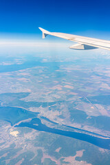 Aerial view from airplane window above green ground. View from the airplane window with beautiful clouds at sunrise