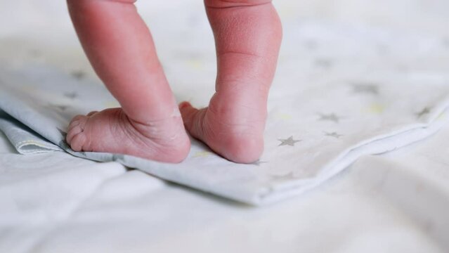 Tiny naked newborn feet on the laid sheet. Checking the child right after birth. Close up.