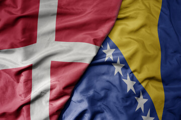big waving national colorful flag of denmark and national flag of bosnia and herzegovina .