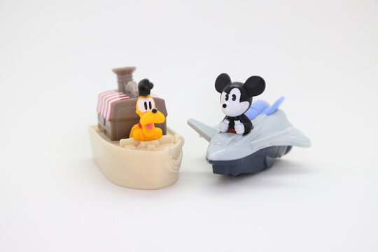Pluto the dog sailing on a steamboat at the Disney World parks and mickey Mouse on a space ship. Collectible toy for children on white background isolated with copy space.