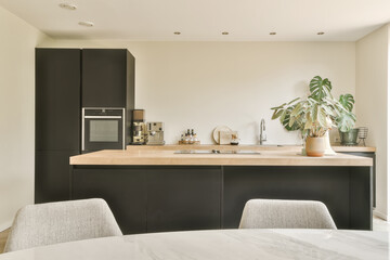 a modern kitchen with black cabinets and white marble countertops in the island is surrounded by a pot of plants