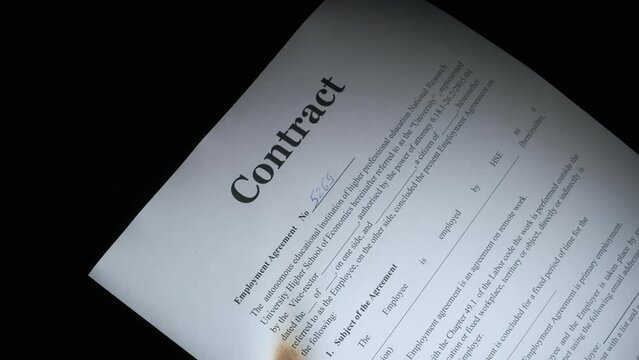 Burns a contract document on black background. Somebody get fire to the contracts paper against black background.