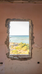 Seashore view from the window of an abandoned house on a sunny summer day.