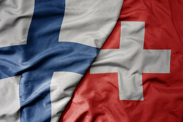 Fototapeta premium big waving national colorful flag of finland and national flag of switzerland .