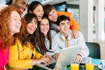 Young group of happy student friends standing together while studying on laptop. Smiling portrait...