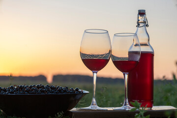 Wine in a glass and bottle on the background of the sunset