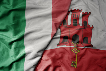 big waving national colorful flag of italy and national flag of gibraltar .