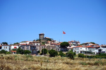 Alte Windmühle aus Naturstein auf einem Hügel vor blauem Himmel mit türkischer Fahne im Wind im...