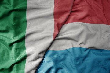 big waving national colorful flag of italy and national flag of luxembourg .