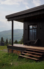 Front view of black modern cabin with terrace on Carpathian mountains in Ukraine