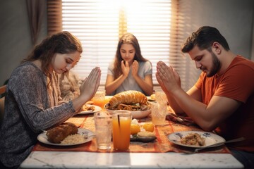 The family gathered around the table prays before eating.