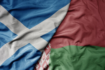 big waving national colorful flag of scotland and national flag of belarus .