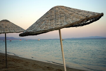 Große runde Sonnenschirme aus Korbgeflecht vor blauem Himmel im Licht der Abendsonne im Sommer am...