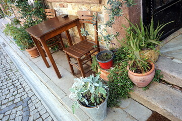 Schöner Holztisch in Braun mit Hocker und dekorative Pflanzschalen vor einem Café und Bistro in...