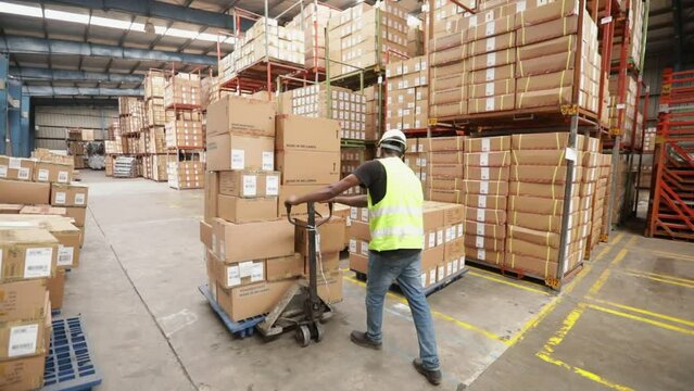 Warehouse Worker Pushes A Hand Pallet Truck With Boxes