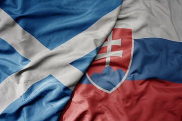 big waving national colorful flag of scotland and national flag of slovakia .