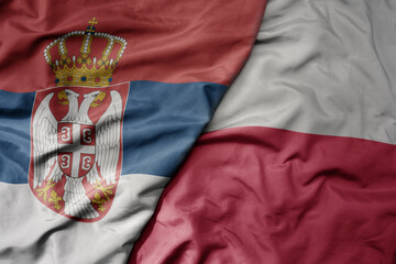 big waving national colorful flag of serbia and national flag of poland .