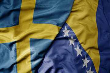 big waving national colorful flag of sweden and national flag of bosnia and herzegovina .