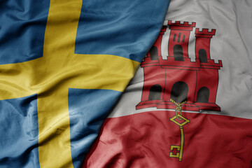 big waving national colorful flag of sweden and national flag of gibraltar .