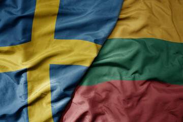 big waving national colorful flag of sweden and national flag of lithuania .