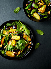 Autumnal plum and spinach salad with toasted walnuts, honey, lime juice and mint leaves. Top view