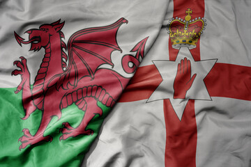 big waving national colorful flag of wales and national flag of northern ireland .