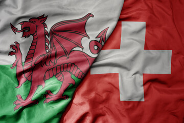 big waving national colorful flag of wales and national flag of switzerland .