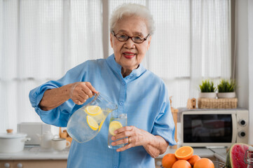 Cheerful grandma with lemonade and other fruit in her kitchen. - Powered by Adobe