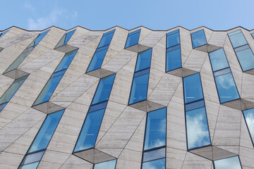 Vertical random pattern of rectangular glass windows and cream granite tile facade. 