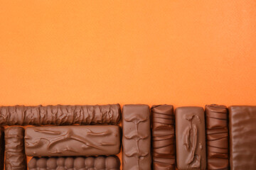 Different tasty chocolate bars on orange background, flat lay. Space for text