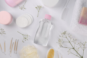 Baby oil in bottle, accessories and gypsophila on white background, flat lay