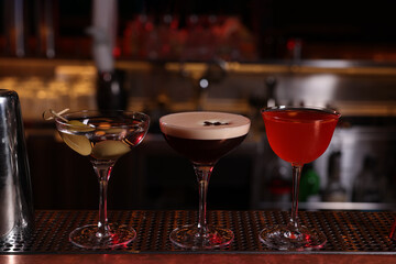 Glasses of different Martini cocktails on bar counter