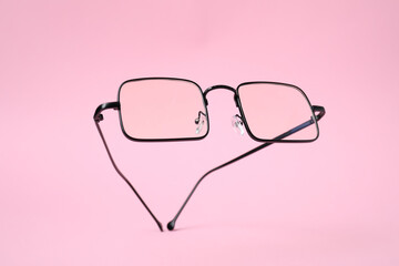 Stylish pair of glasses with black frame on pink background