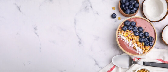 Smoothie bowl with muesli, shredded coconut and blueberries on white marble table, flat lay. Banner design with space for text