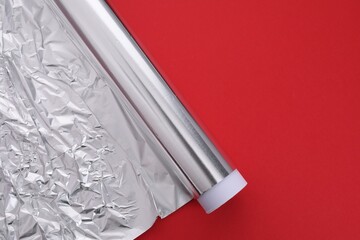 Naklejka premium Roll of aluminum foil on red background, top view. Space for text