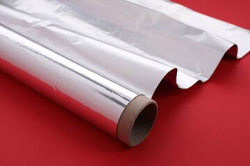 One roll of aluminum foil on red background, closeup