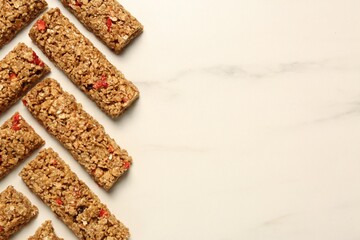 Tasty granola bars on white marble table, flat lay. Space for text