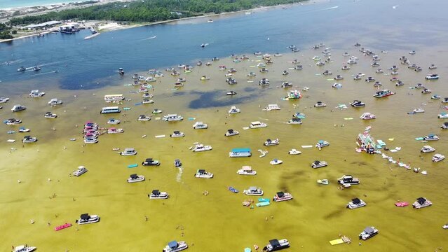 Crowd of people enjoy boating, pontoons, jet skis, paddleboards, swimming, wading shallow Crab Island, Destin, Floria low tide brackish water, Okaloosa Island Grass Flats