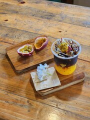 Ice americano with orange juice  and passion fruit  on top. Decorate ith  Flower .The cup put on the old wood table