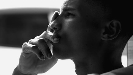 One contemplative young black man gazing at sky in meditation, thinking deeply about life, pondering decision in dramatic black and white