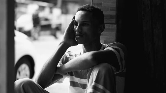 One young lonely black man feeling isolation and loneliness in dramatic monochromatic, black and white. African American male struggles with social alienation and depression