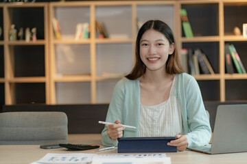 Asian woman using laptop computer and working at office with calculator financial documents on table Planning analysis of financial reports in the office
