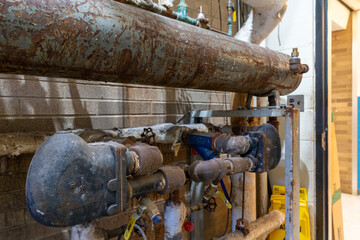 Old corrosion rusty valve piping, tank, steam HVAC heating system within a municipal building.
