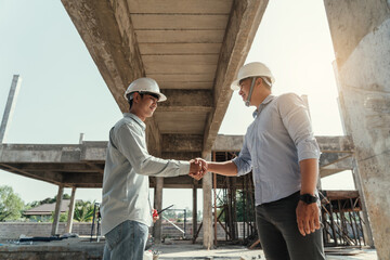 Architect and engineer construction workers shaking hands while working for teamwork and...