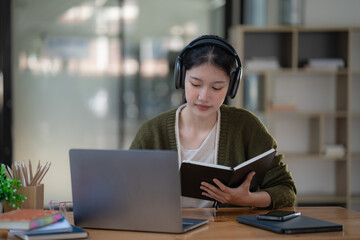 Asian women wearing headphones study online watch webinar podcasts on laptops listen to learning education course conference calling, and e-learning concepts.