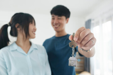 Happy young couple buying a new house receiving the keys.